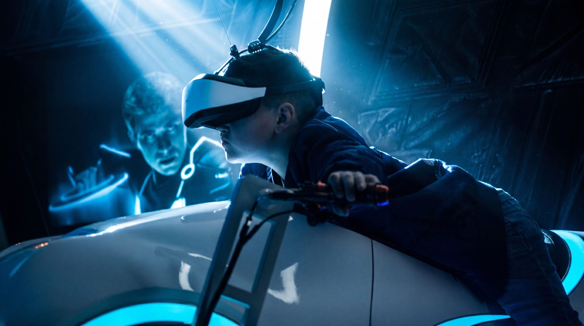 A kid in a VR headset leaning into the Light Cycle, the room glowing cyan